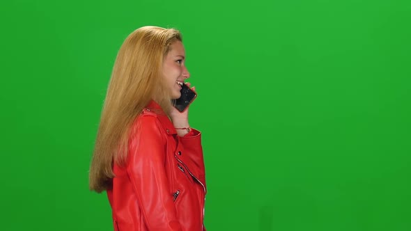 Portrait Blonde Girl Is Calmly Walking and Talking on Mobile Phone at Greenscreen. Chroma Key