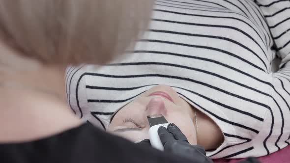 Cosmetologist, beautician making facial treatment with ultrasonic spatula