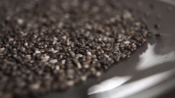 Chia seeds fall in slow motion on a shiny saucer