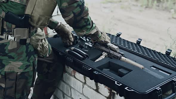 The Soldier Pulls a Rifle Out of the Ammunition Case and Insert Ammunition Clip Into Assault Rifle