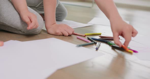 Close Up of a Pencils and White Paper Where and Hands and Feet of a Little Boy and a Little Girl Who