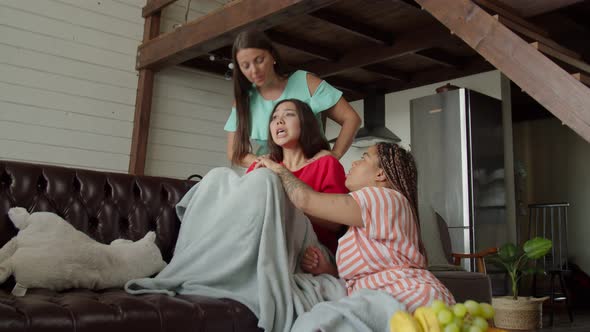 Multinational Friends Cheering Up Crying Woman Sitting on Sofa at Home