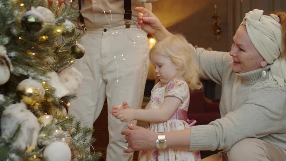 Little Girl and Grandparents Decorating Christmas Tree