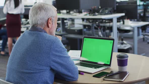 Rear view of man using laptop at office