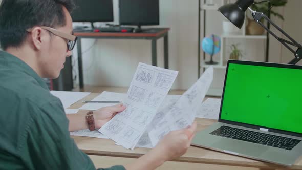 Creative Designer Works On A Storyboard, Looks At His Sketches With Mock Up Green Screen Laptop