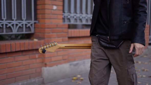 Man Walking Down the Street with a Guitar