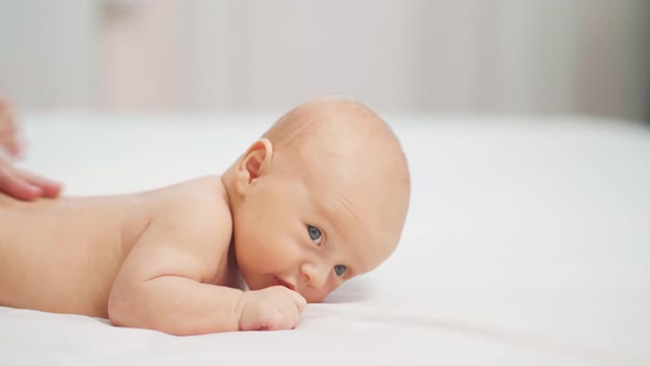 the Baby Lies on His Tummy on a White Sheet