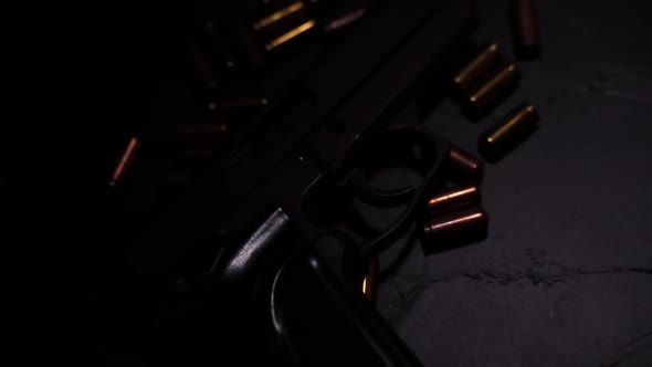 Flashlight Illuminates Hand Gun and Bullets on Black Concrete Table