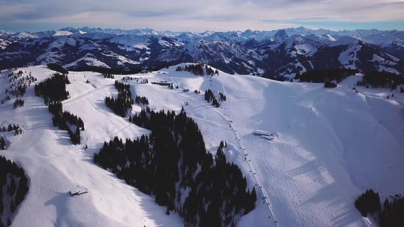 Snowy mountains in low clouds and blue sky at sunset in winter. Panoramic landscape with beautiful s