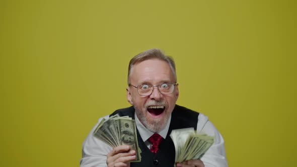 Joyful old man holding paper banknotes in his hands. Funny senior man with open eyes and mouth holds