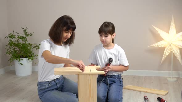 Happy Family Mother and Daughter Assembling Wooden Furniture Together with Screwdriver