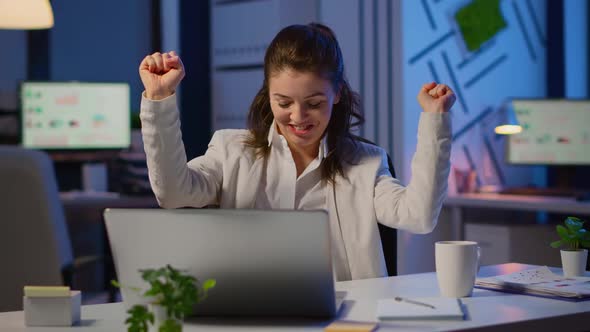 Happy Freelancer Receving Good News on Laptop Working Overtime