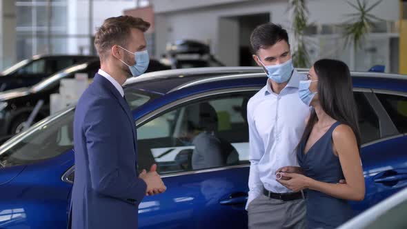 Happy Couple in Masks Taking Car Key at Showroom