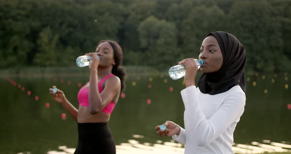 Black Female Friends Drinking Water After Running in Summer