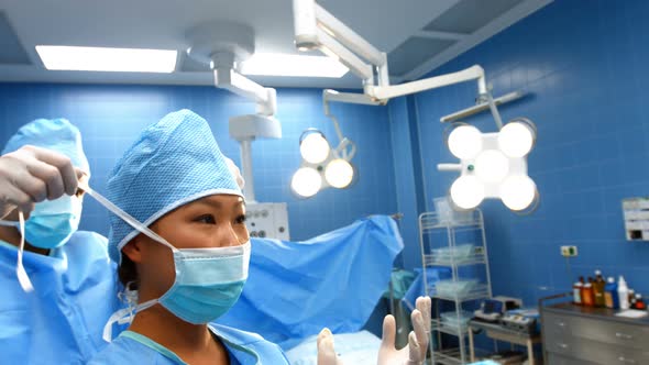 Surgeon assisting in tying surgical mask