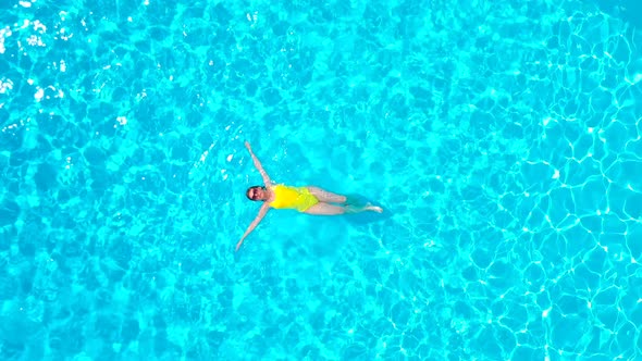 View From the Top As a Woman in a Yellow Swimsuit Lying on Her Back in the Pool