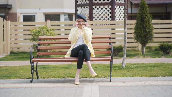 Wide Shot of Elegant Blond Woman Putting on Sunglasses, Standing Up From Bench and Leaving. Portrait