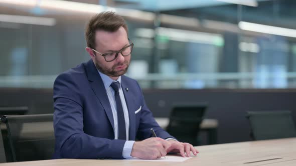 Hardworking Middle Aged Businessman and Writing on Paper