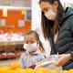 Young woman with child girl in medical masks buys a oranges at supermarket - VideoHive Item for Sale