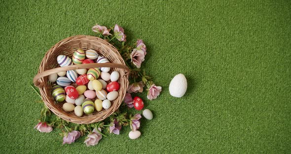 Basket with Many Coloured Eggs on Green Grass Background