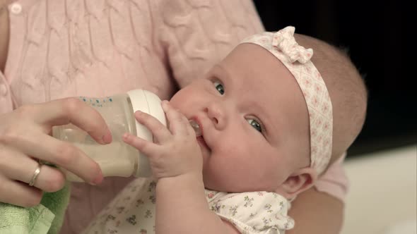 Young Mother Is Feeding Her Baby Milk