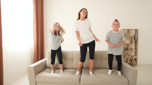 Mom Plays with the Children They Jump on the Couch Have Fun and Hug