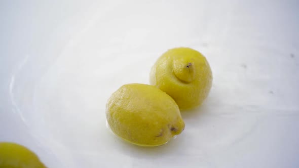 SLOMO of Lemons in Water on White Backdrop