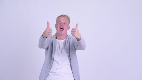 Happy Young Blonde Man Giving Thumbs Up and Looking Excited