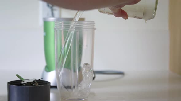 Male pouring water into generic blender cup