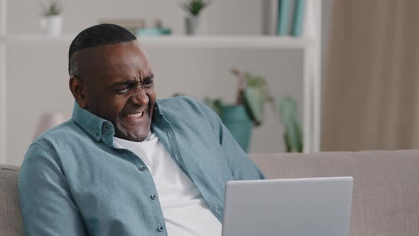 Adult African American Man Sitting Looking at Laptop Screen Puzzled Worried Funny Expression Froze