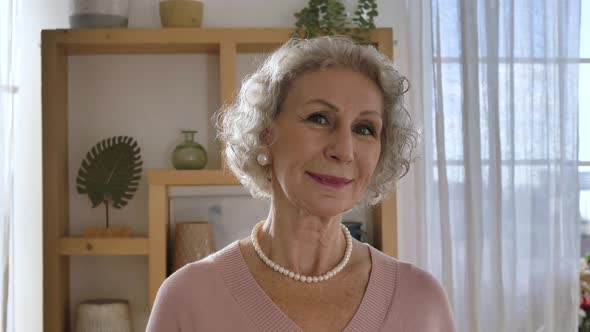 Elegant Retired Woman Looks Into Camera and Smiles Gently