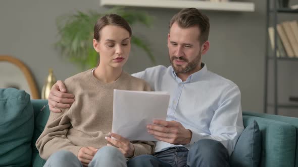 Couple Reading Documents Together on Sofa