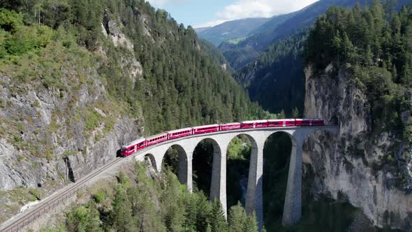Aerial View of a Moving Red Train Along the Landwasser Viaduct in Swiss Alps