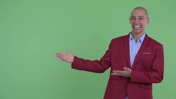 Happy Bald Multi Ethnic Businessman Showing Something and Looking Excited