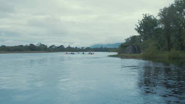 Group of kayakers out paddling on river, Wide tracking shot