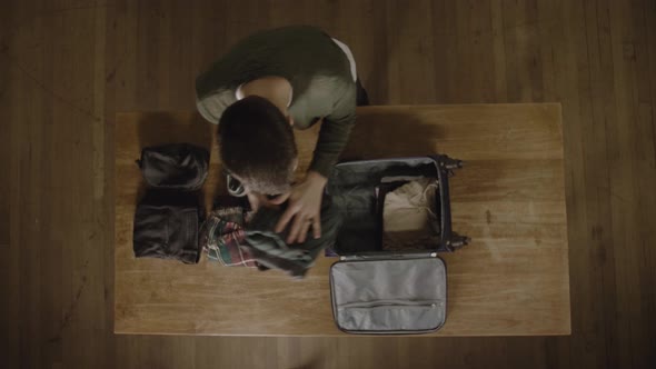 Young man packing his carry on bag for a last minute trip. Overhead view.