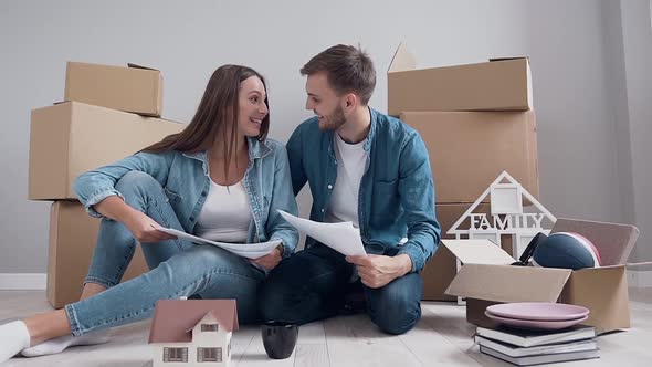 Young Couple which Sitting on the Floor and Planning About Their New Life in New Apartment