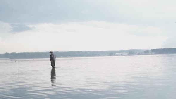 Fisherman Standing Hip High Deep in the Sea Holding Fishing Rod Action