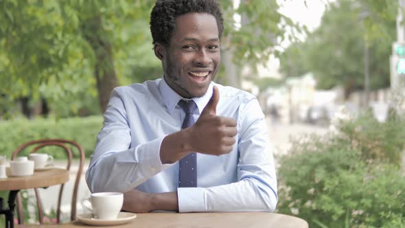 Thumbs Up by African Businessman Sitting in Outdoor Cafe