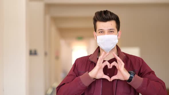 Happy doctor in protective mask on face gesturing heart symbol by hands. 