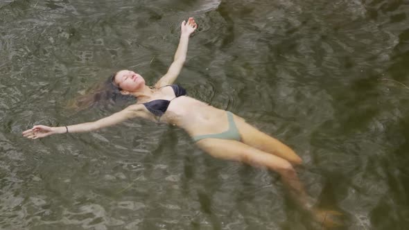 Caucasian woman having a good time on a trip to the mountains, wearing bathing suit and floating on