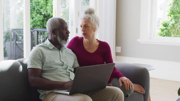 Mixed race senior couple using laptop in the living room at home
