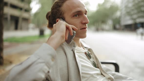 Laughing curly-haired man talking by phone