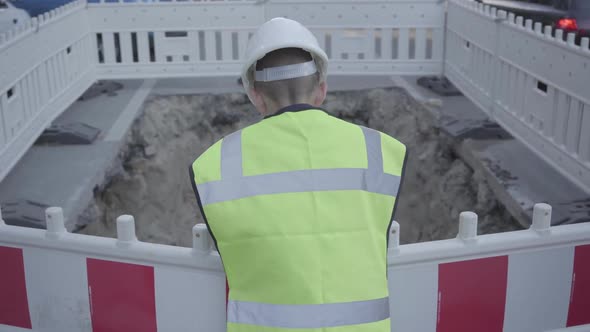 Confident Small Boy Wearing Safety Equipment and Constructor Helmet Standing on the Road and Checks