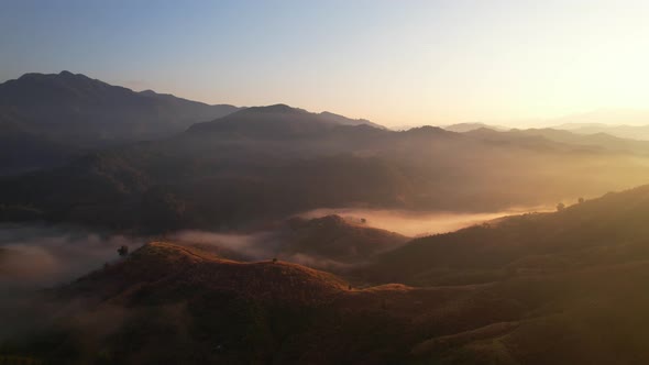 4K aerial view over a misty mountainous area. The great golden sun in the morning