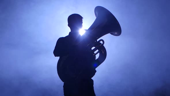Trumpeter in Spotlight in Smoky Studio Plays on Tuba. Closeup