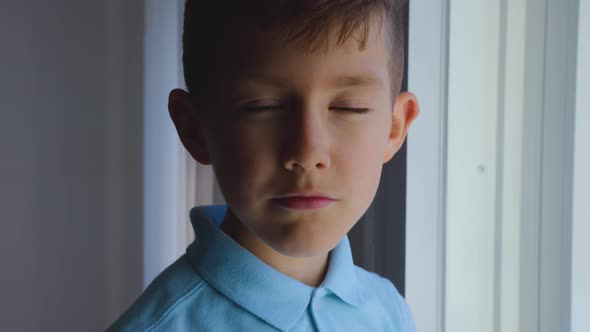 Sad Child Looks Out the Window the Boy is Waiting Looking at Camera