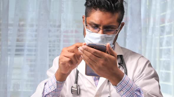Doctor in Protective Mask Using Smartphone in the Hospital.