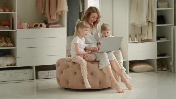 Mom with Daughters Blonde Twins Sitting at a Laptop