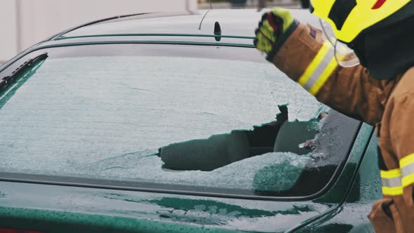 Car Accident Rescue, Firefighter Breaking the Glass on the Car. Close Up, Slow Motion Shot